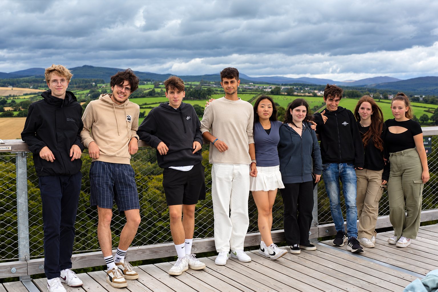 Group of international students posing on a viewing platform overlooking green Irish countryside