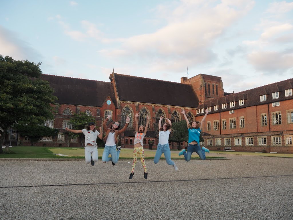 Junior campers jumping for joy in front of Ardingly College's historic building during summer camp in England