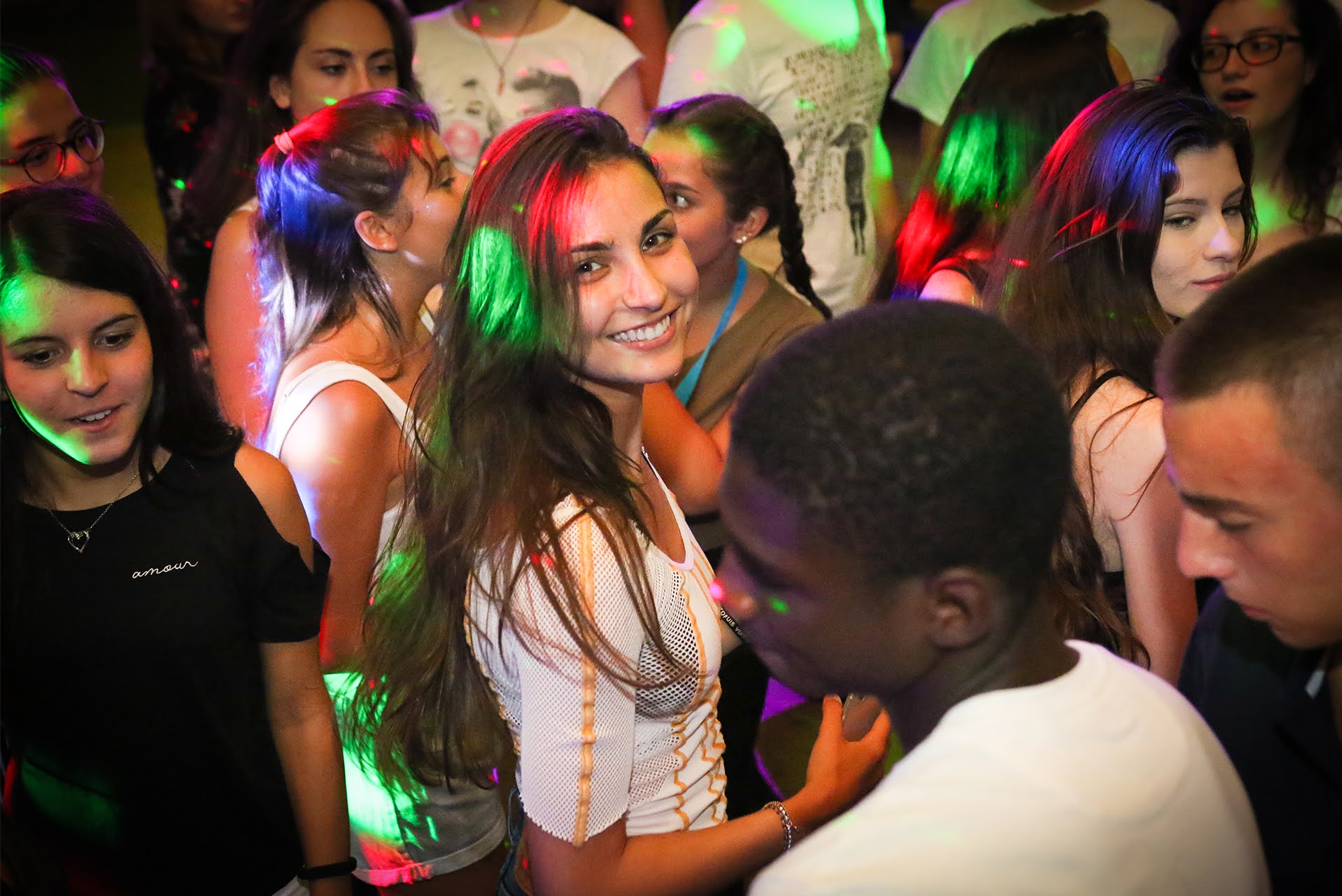 Teen students dancing under colorful disco lights at an evening party during Dublin summer camp
