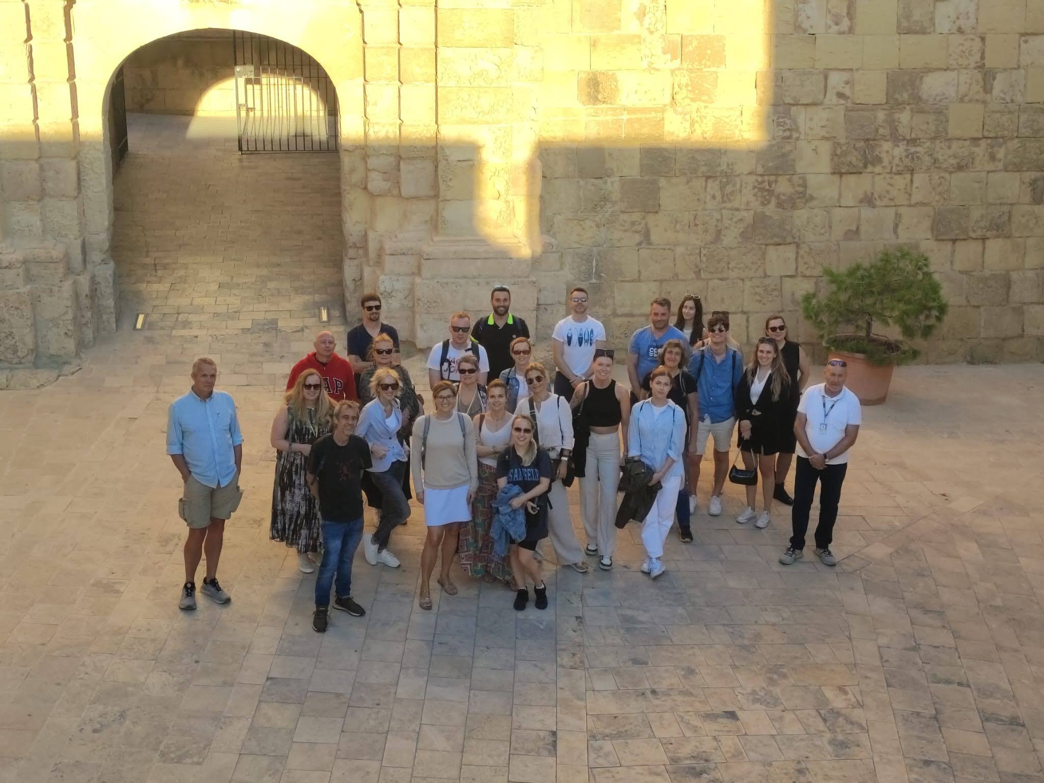 Adult students group posing outside a historic Malta fortress during a guided tour