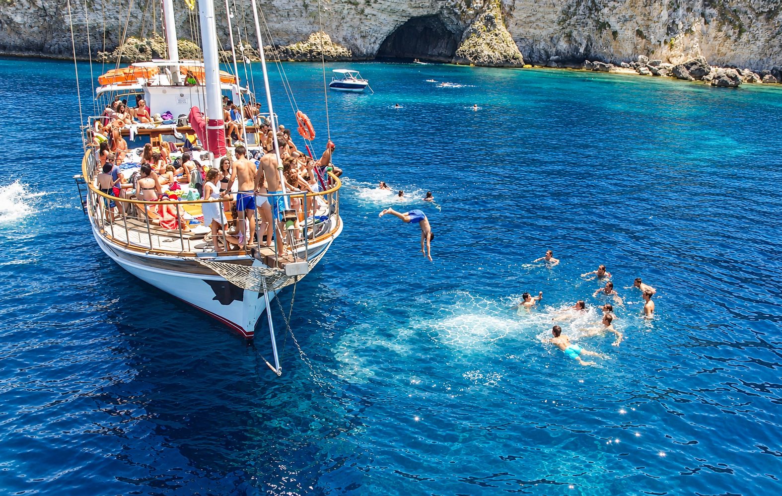 Students diving off a sailing boat into turquoise waters during a Malta language course excursion