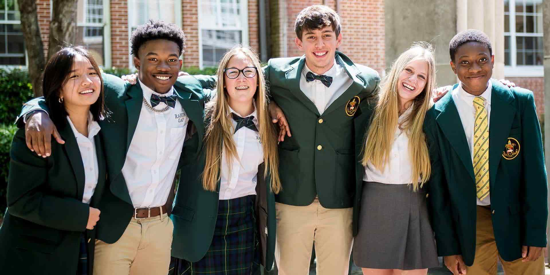 International students in green blazer uniforms smiling together at a US boarding school