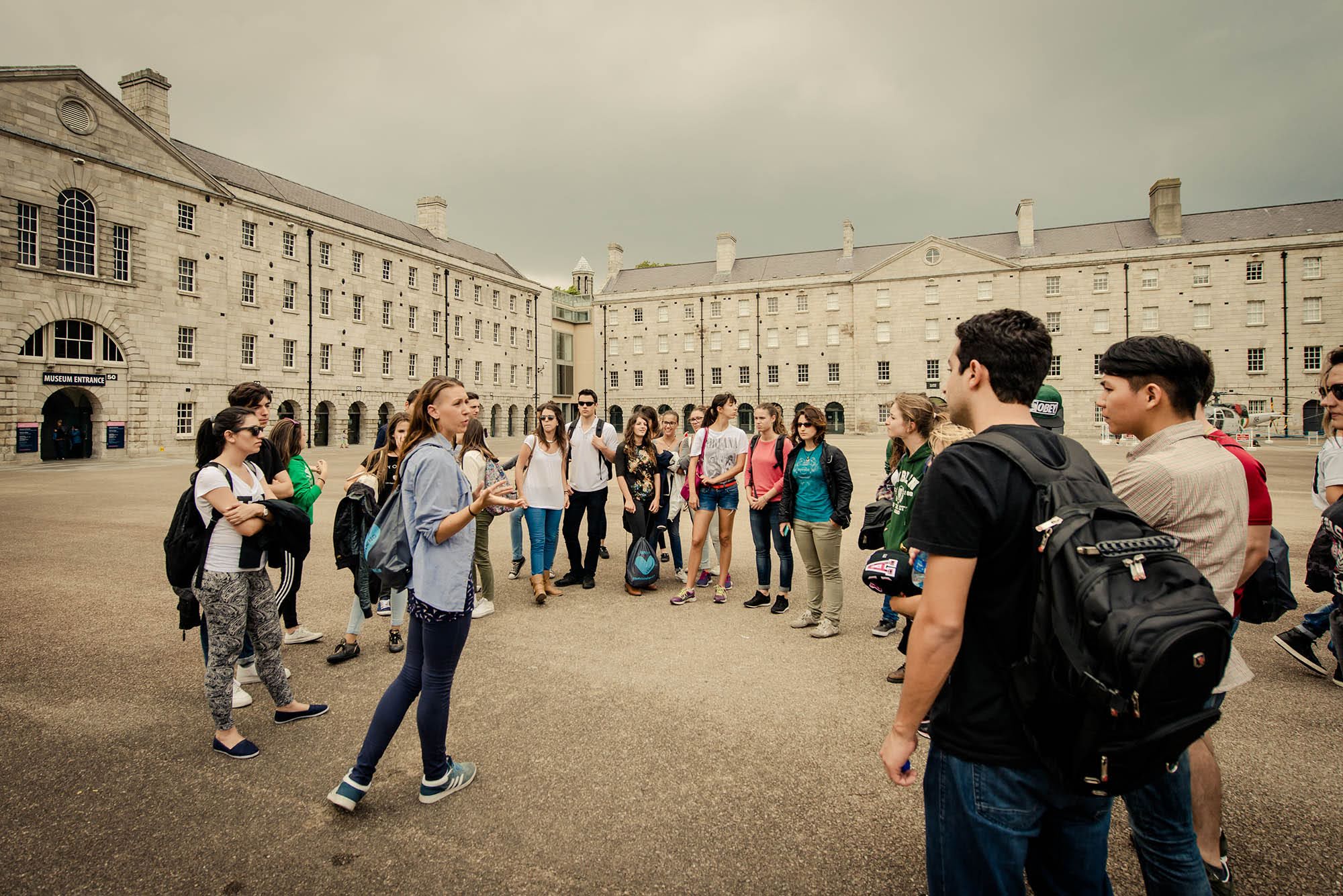 Adult students gathered around a guide during a museum courtyard tour in Ireland