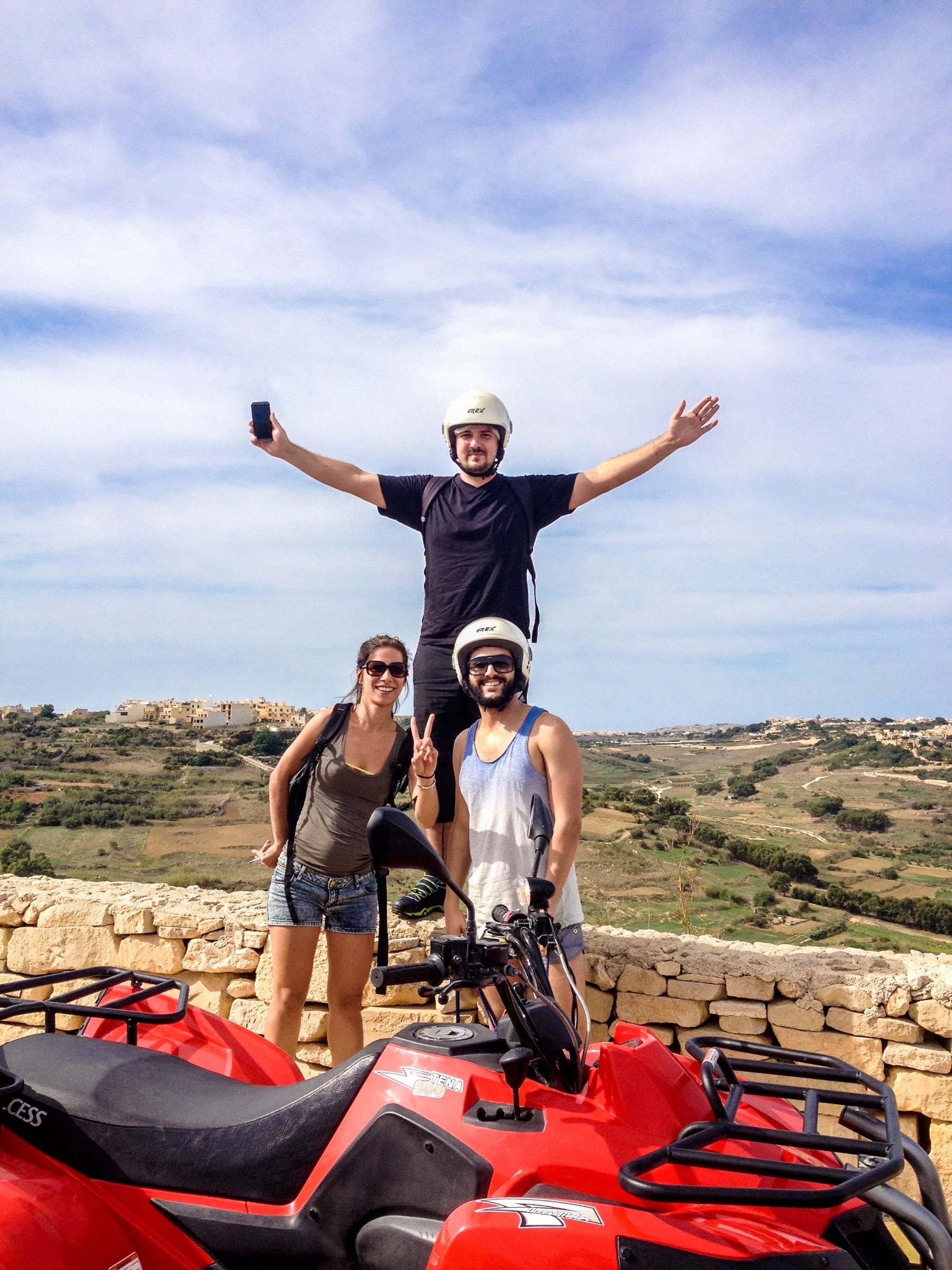 Adult students celebrating on a quad bike tour overlooking the Maltese countryside
