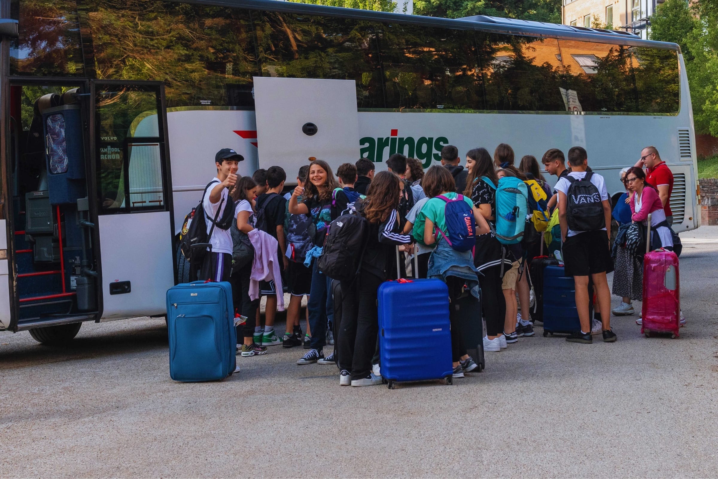 Teen students with suitcases boarding a coach for their Exeter junior summer camp