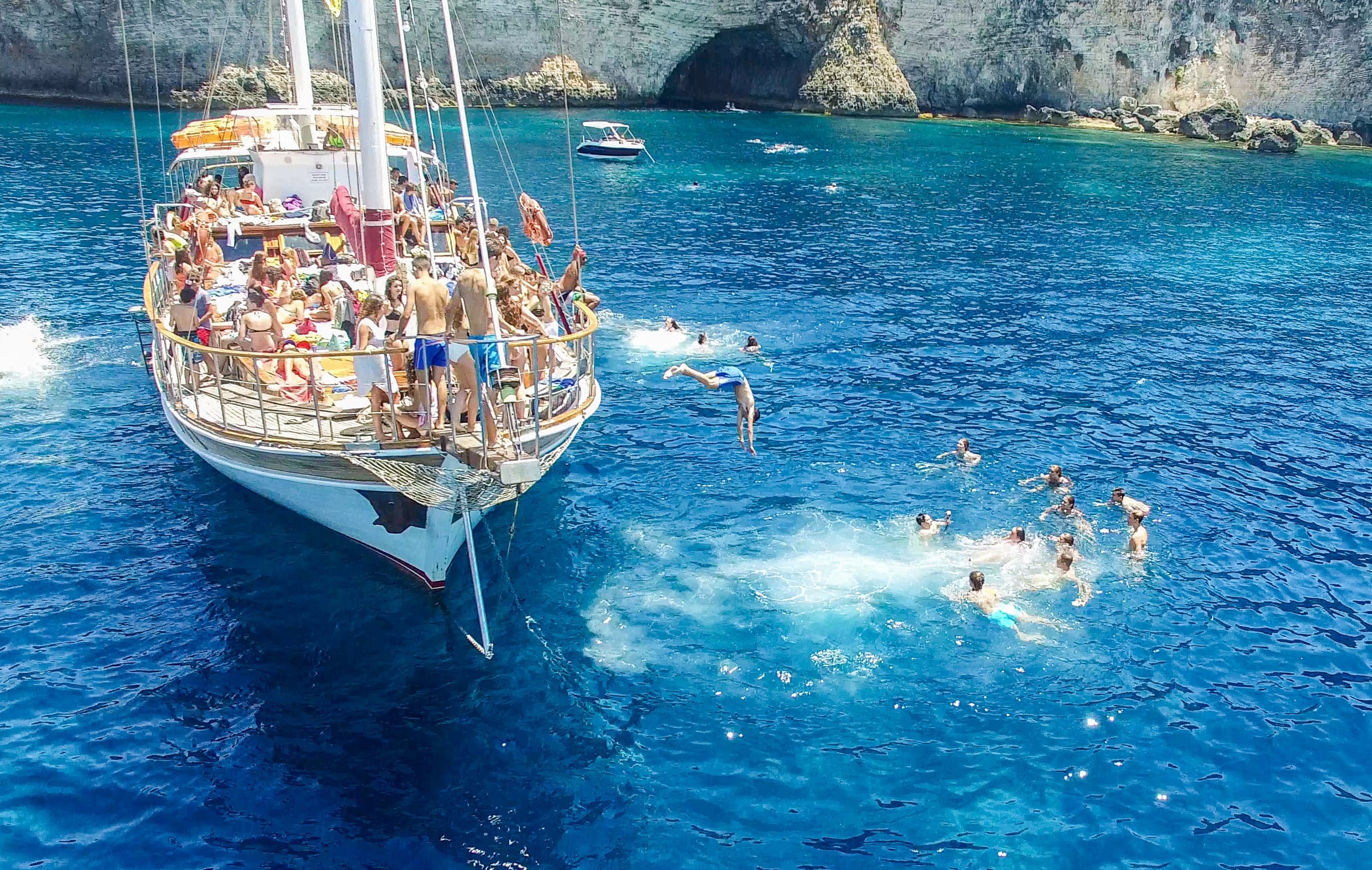 Teen students diving off a boat into Malta's clear blue waters during a summer excursion