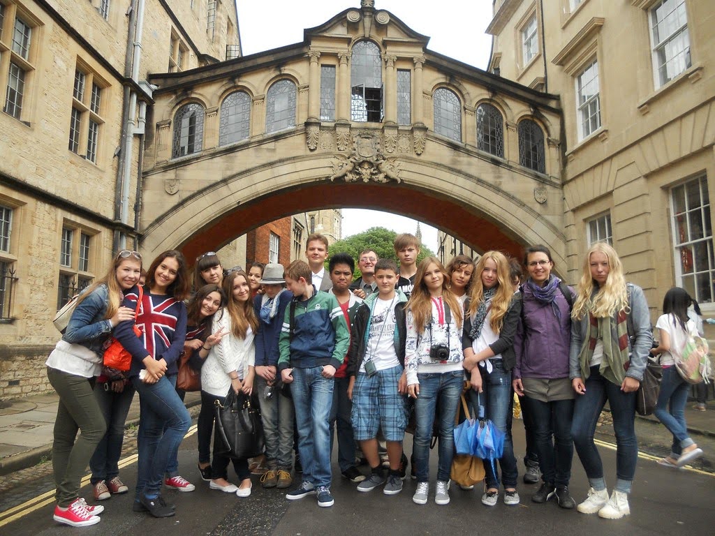 Junior students posing beneath Oxford's Bridge of Sighs during a group excursion in England