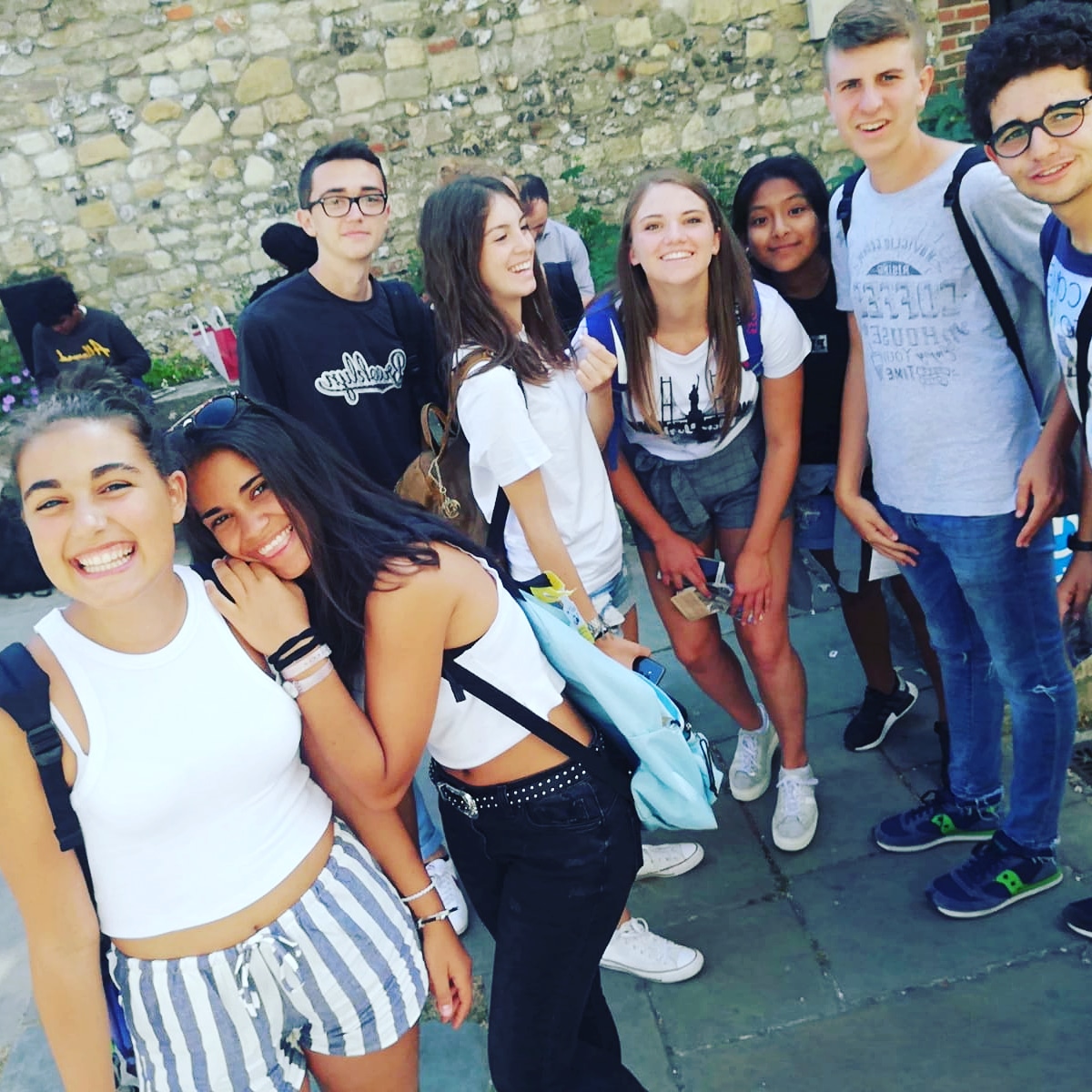 Junior students smiling together during a group excursion near Chichester's historic stone walls
