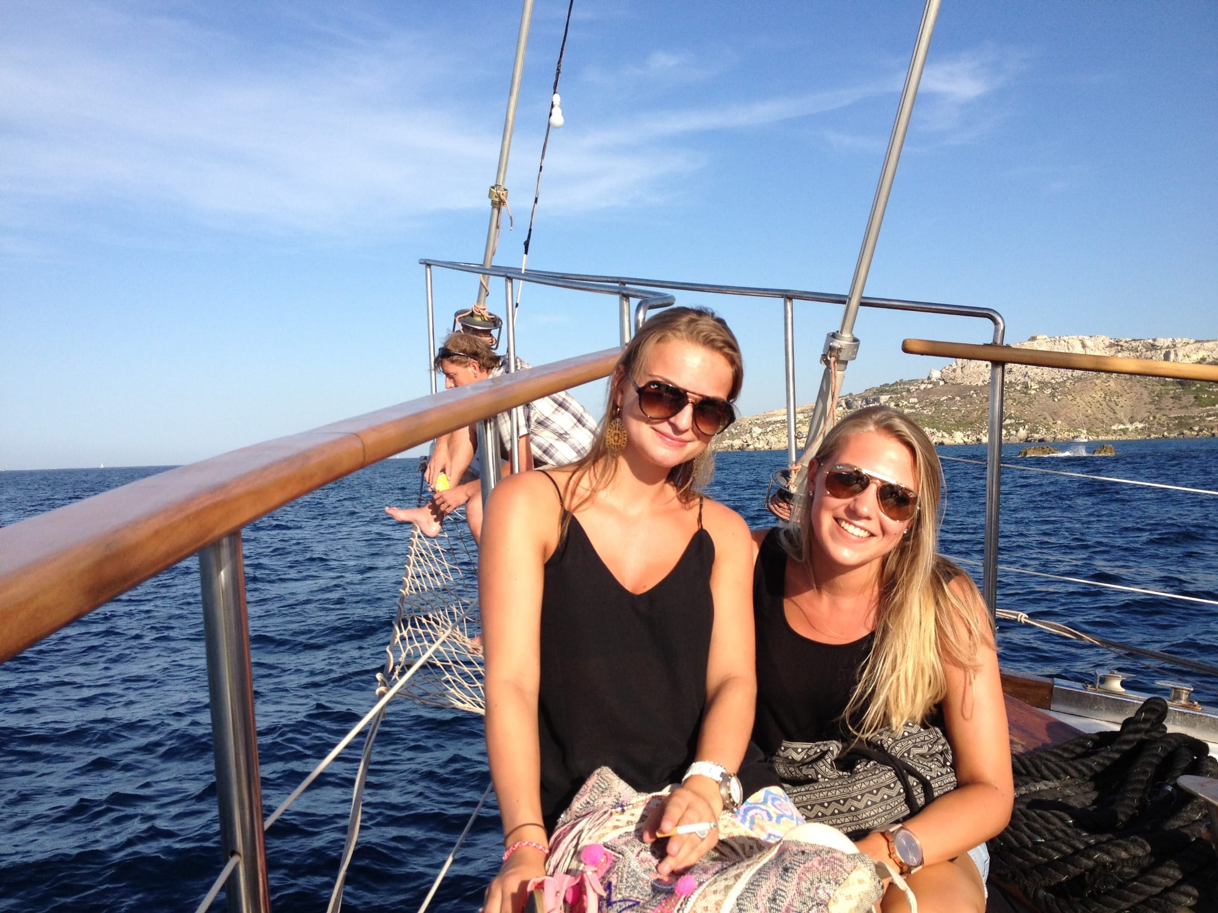 Two teen students smiling on a sailing boat trip along Malta's coastline