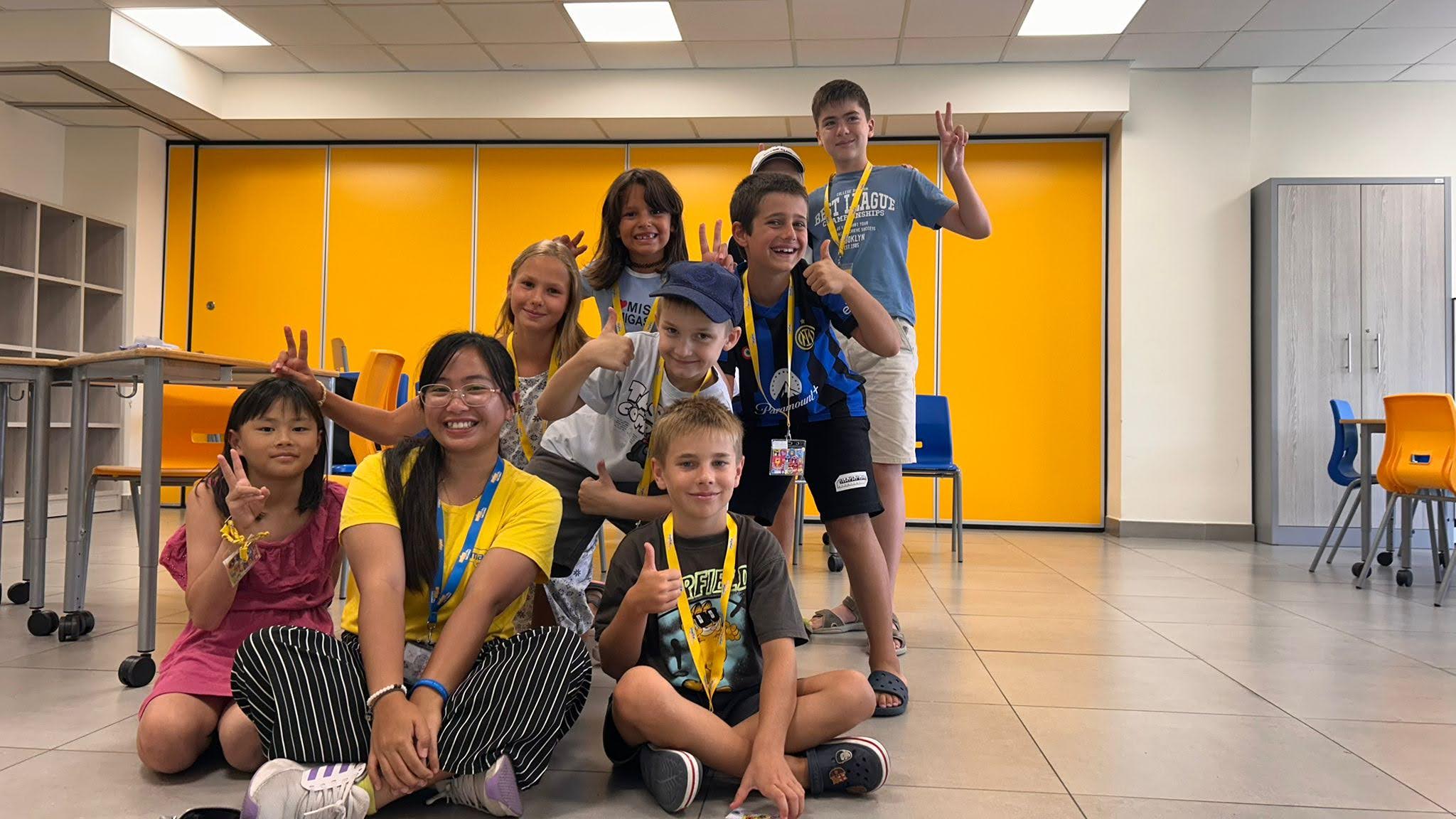 Junior students with lanyards posing cheerfully in a classroom at a Malta language school