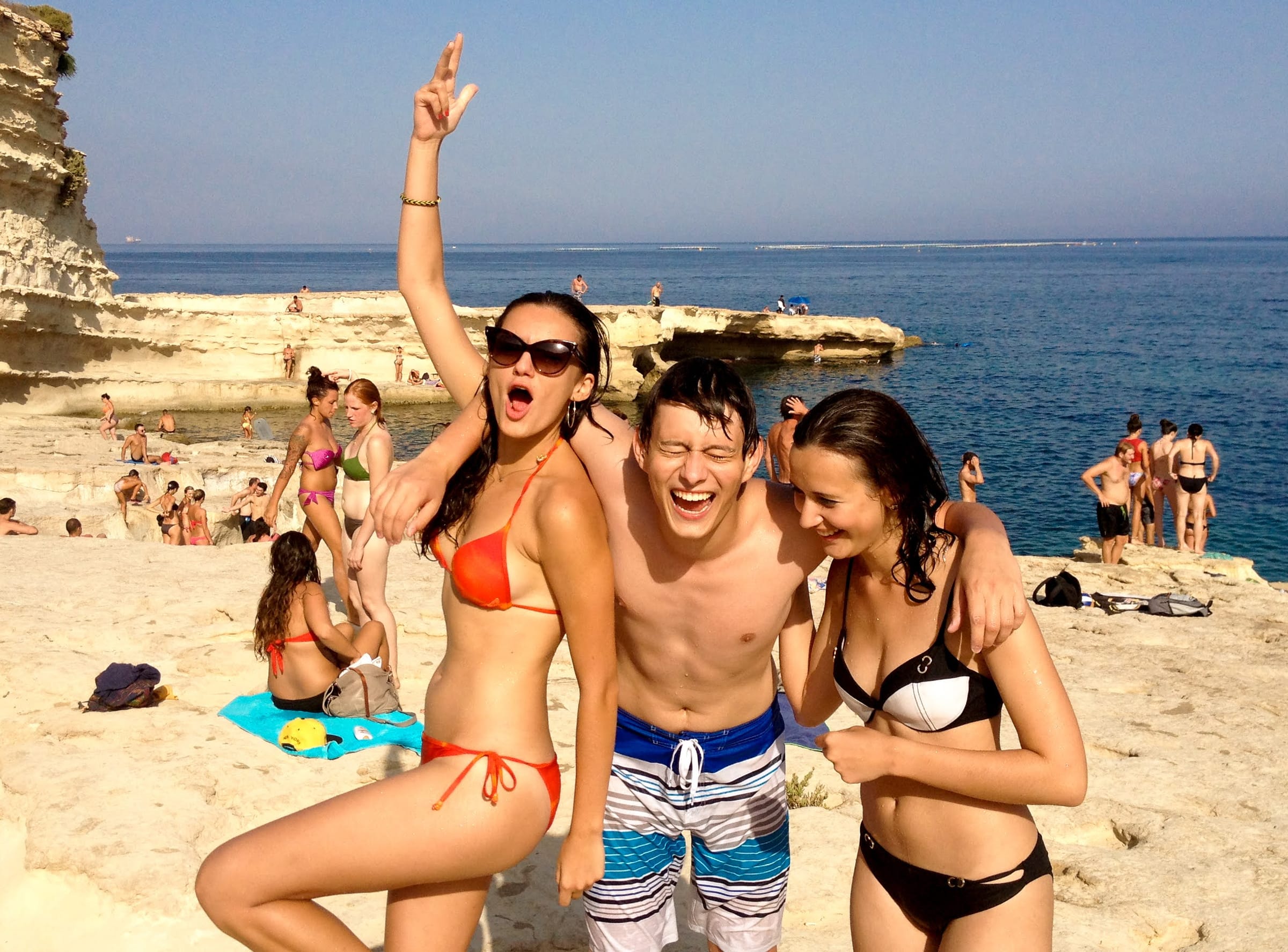 Friends laughing together on the limestone rocks of Malta's coastline