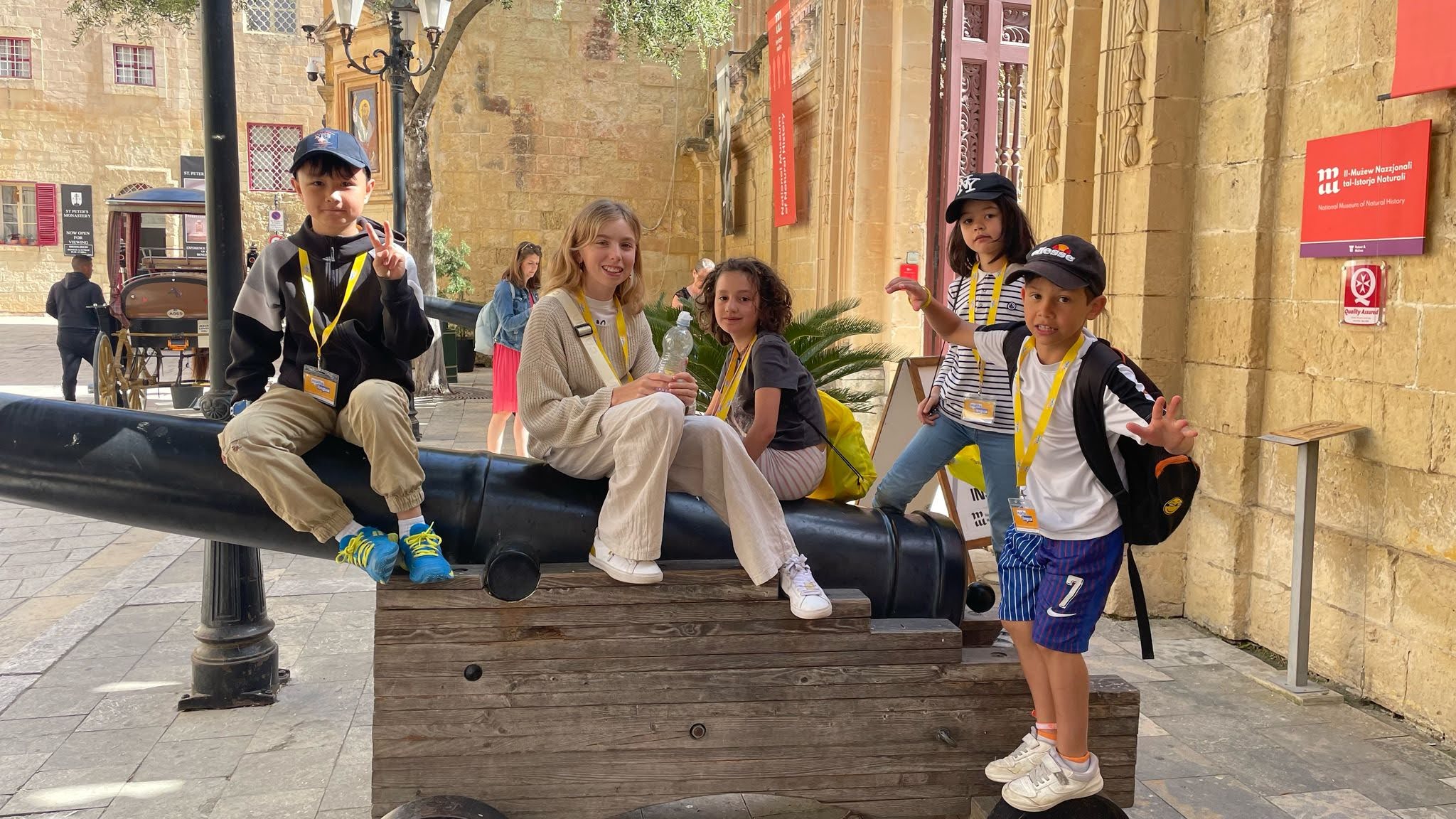Junior students posing on a historic cannon outside Malta's National Museum of Natural History