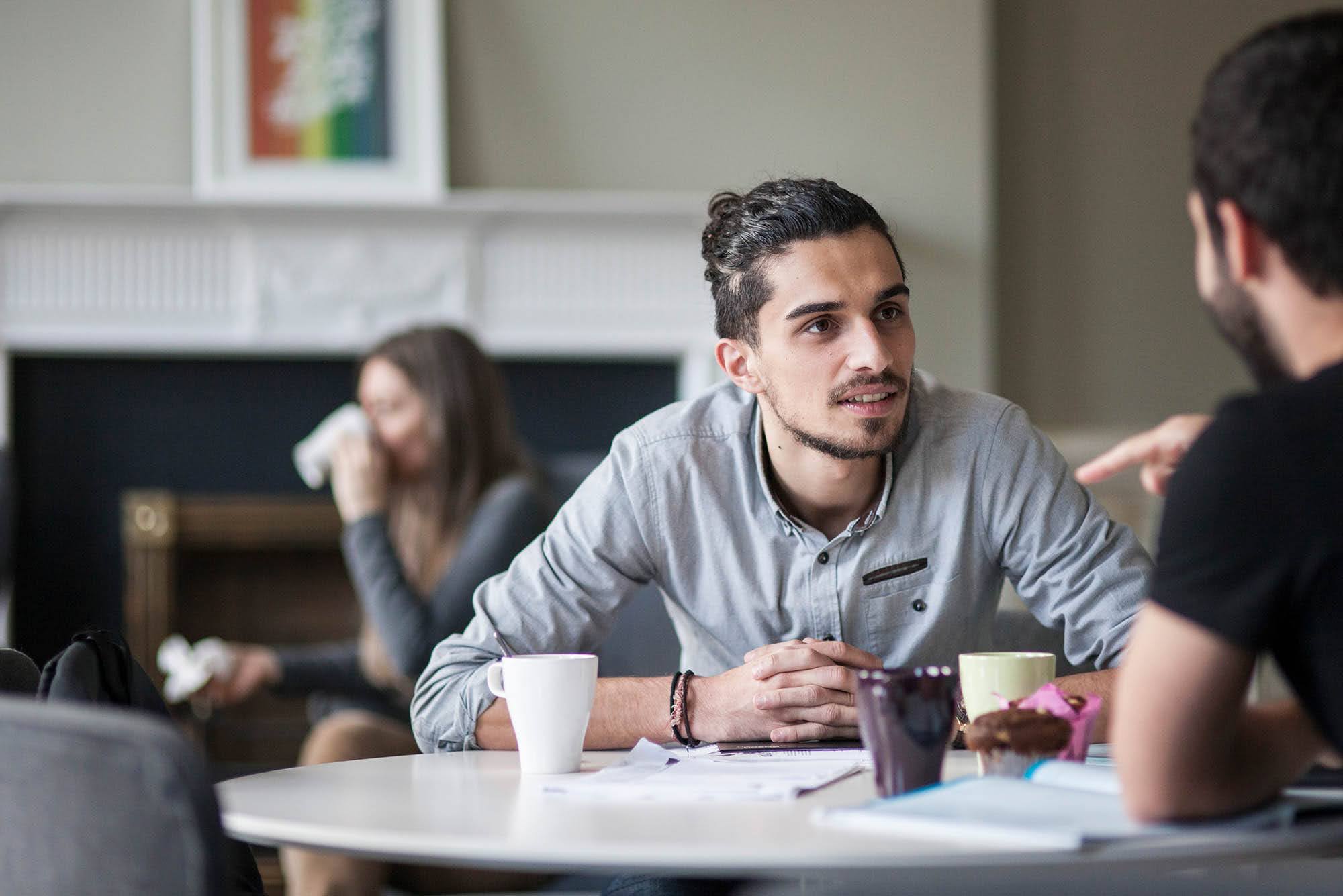 Adult student discussing coursework with classmates over coffee at ISI Dublin's Parnell Square school