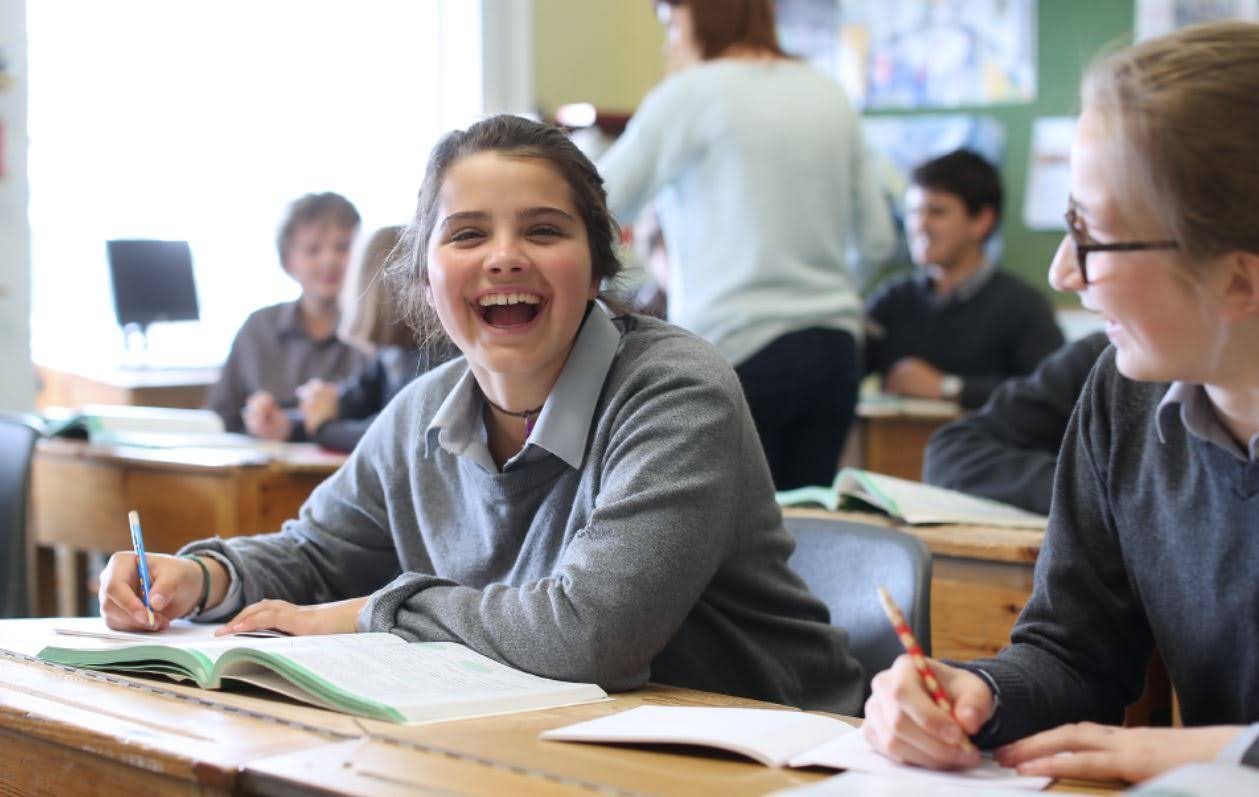 Smiling student in uniform laughing with classmates during a lesson in Ireland