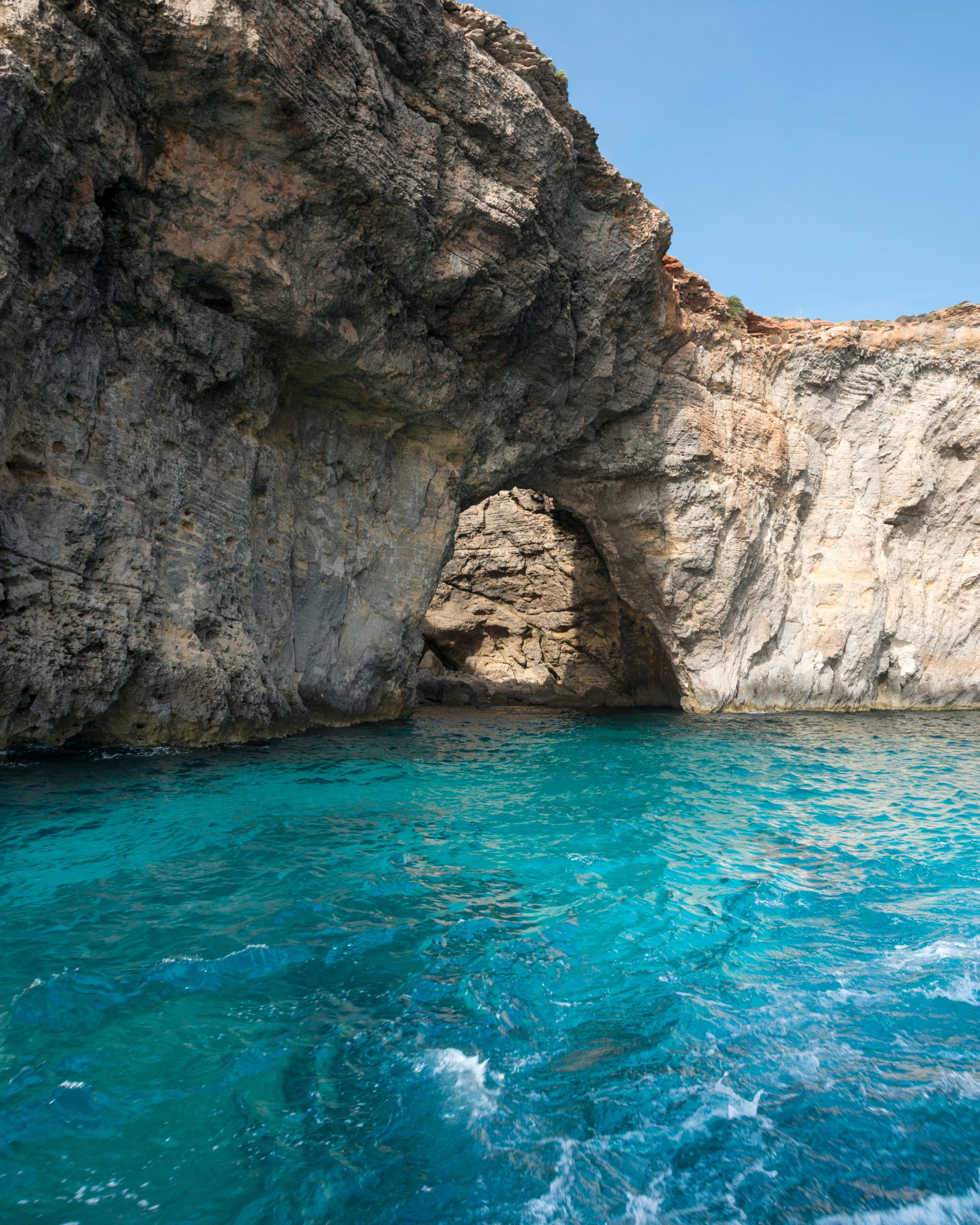 Turquoise waters and natural rock arch along Malta's coastline near the Blue Grotto