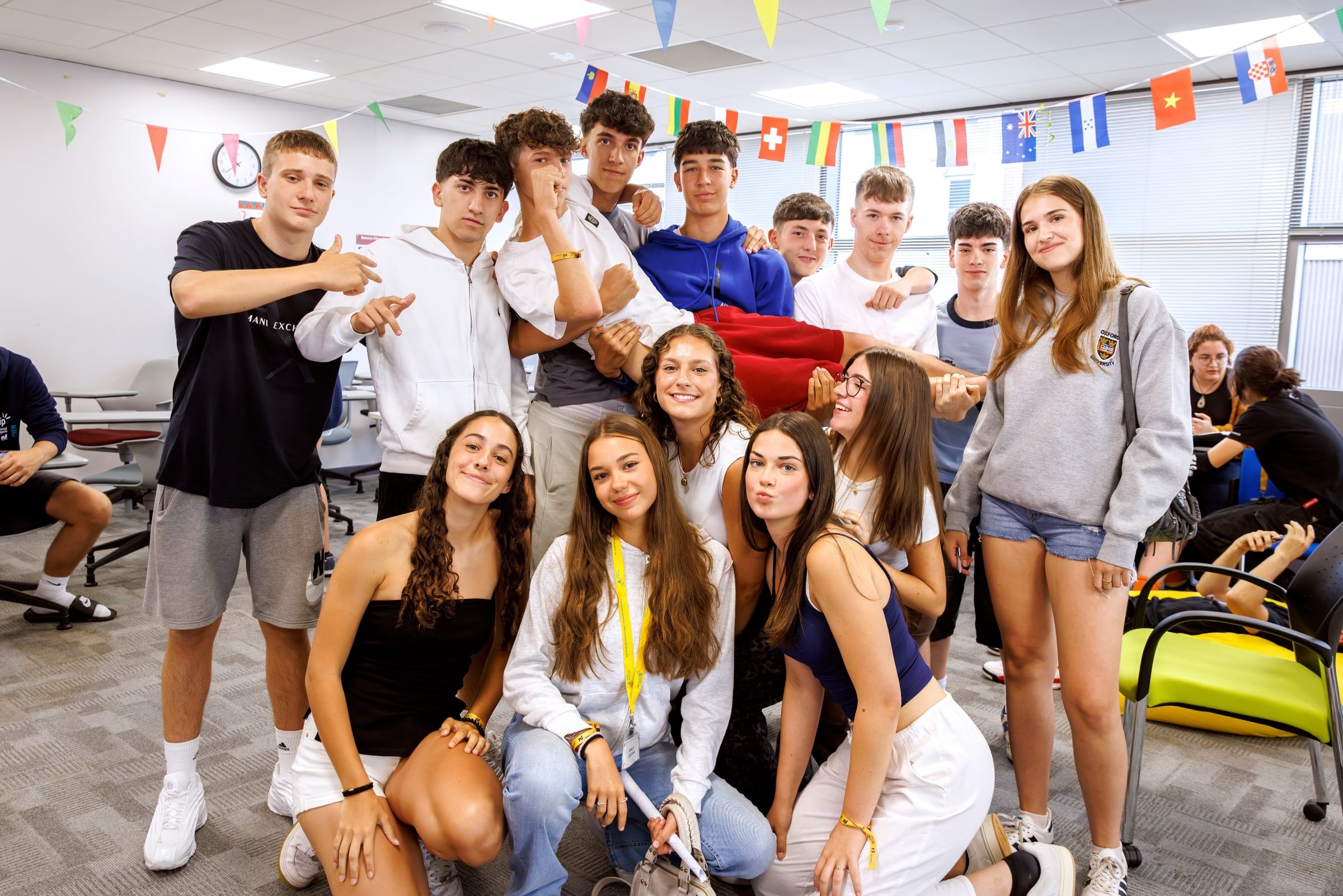 International teens pose together in a flag-decorated classroom at a Southend-on-Sea junior summer camp