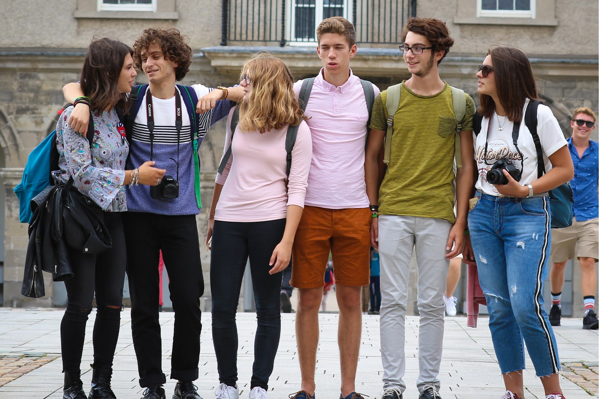 Teen students with backpacks and cameras posing together during a Dublin summer camp excursion