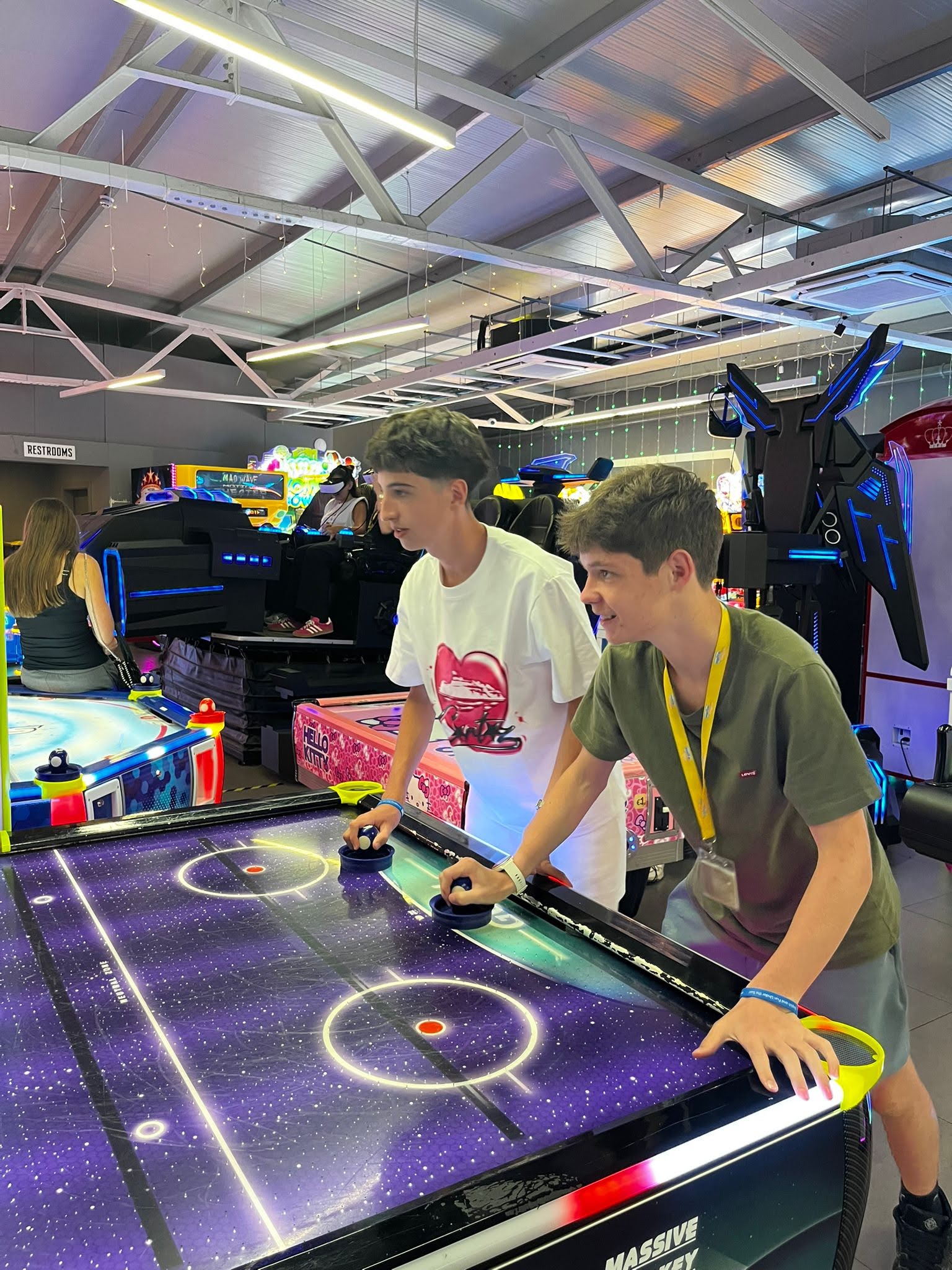 Teenage boys playing air hockey at an arcade during a Malta junior language course excursion