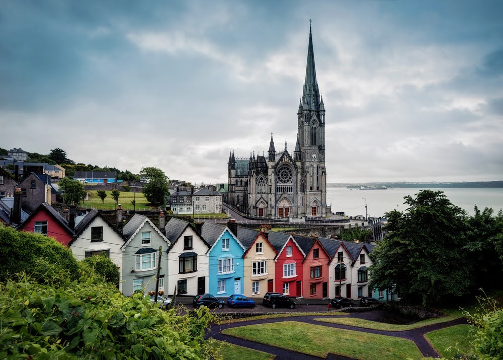 Row of colorful houses beneath St. Colman's Cathedral spire in Cobh, Cork, Ireland