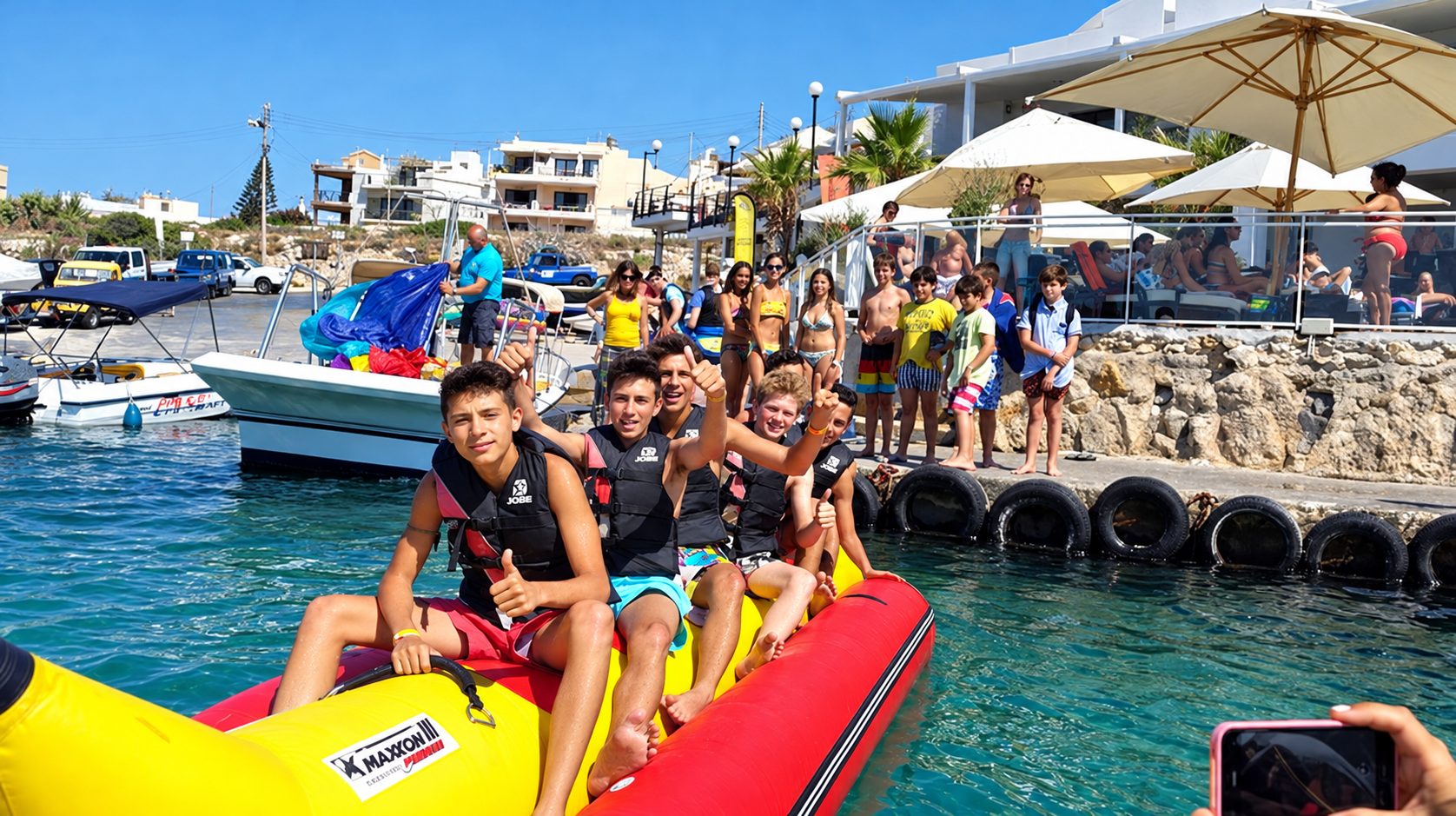 Teen students in life jackets give thumbs up on an inflatable banana boat during a Malta language trip