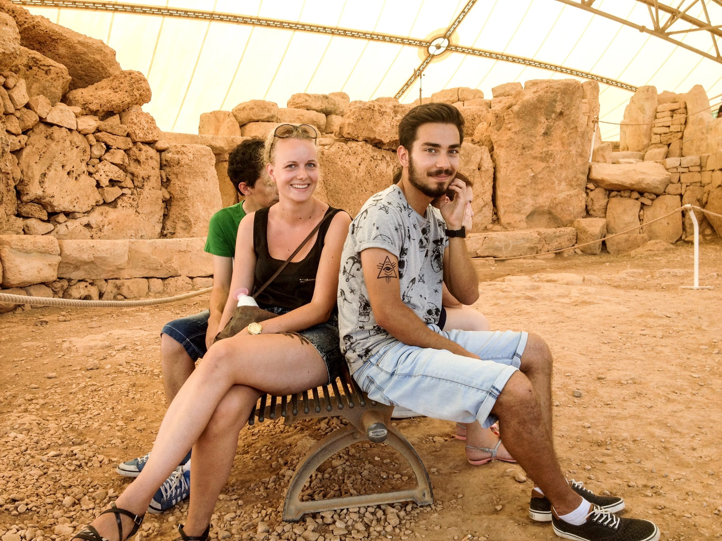 Young adults sitting on a bench while visiting the Hagar Qim megalithic temples in Malta