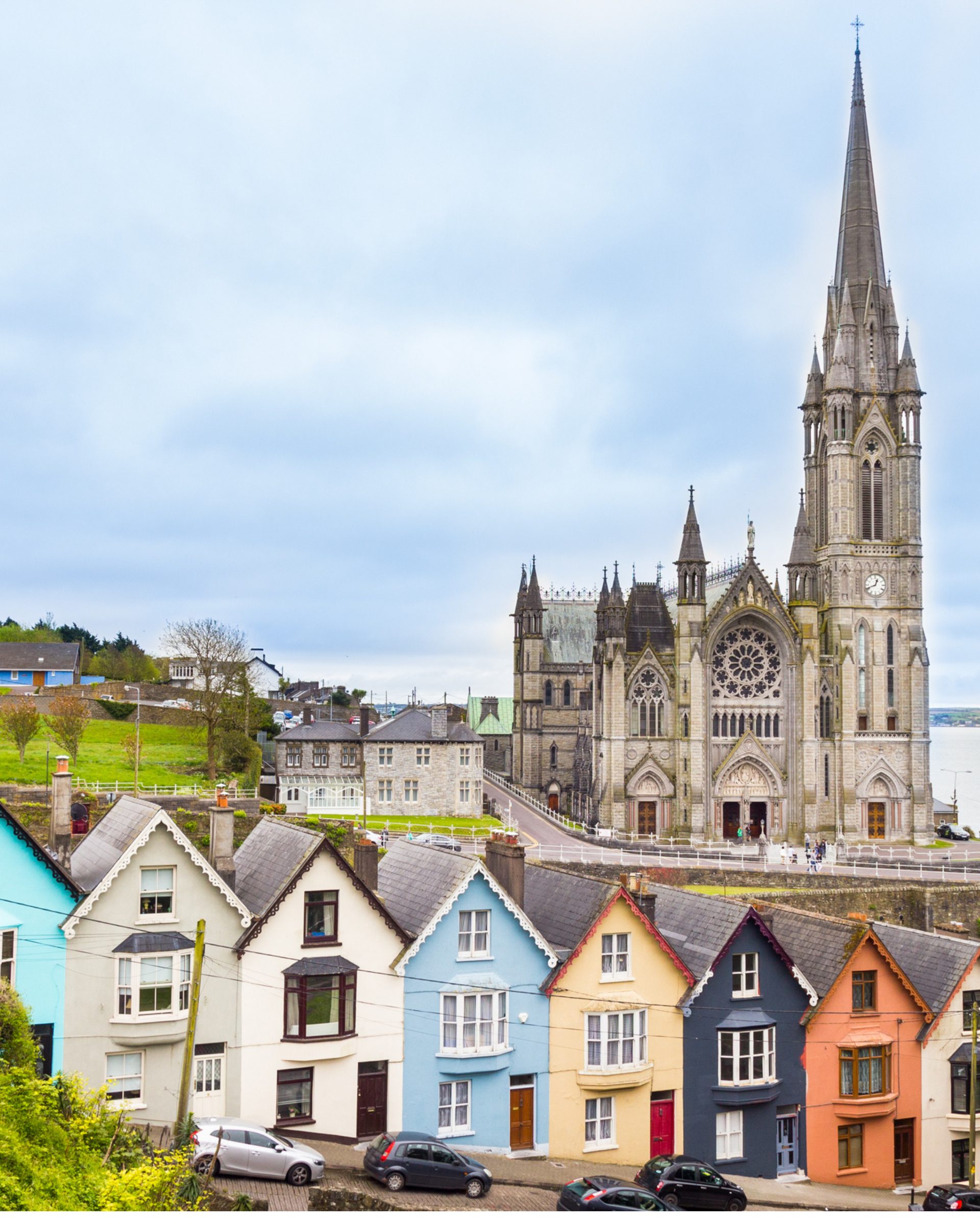 Colorful terraced houses in Cobh, Ireland with St Colman's Cathedral spire rising behind