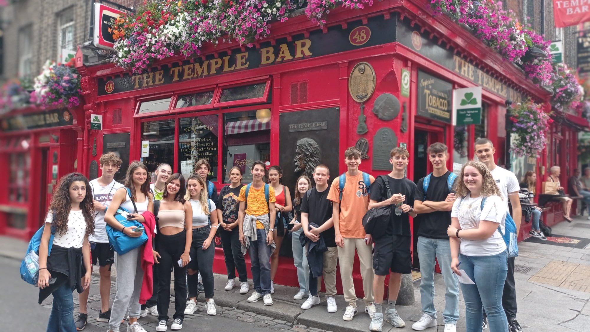 Group of teenage students posing outside the famous red Temple Bar pub in Dublin, Ireland