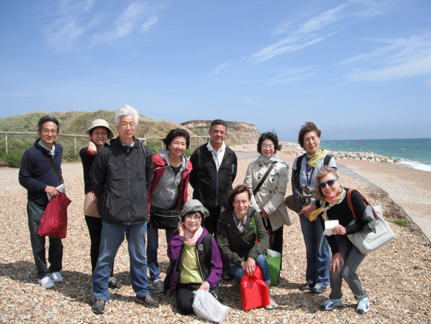 Group of adult students posing together on a pebble beach during a Malta study trip excursion