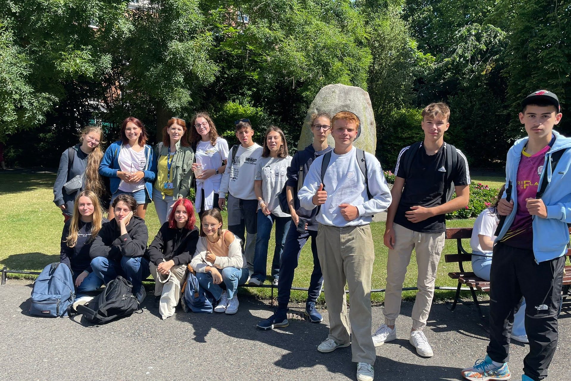 Junior summer camp students posing by a stone monument in a Dublin park during ISI activities