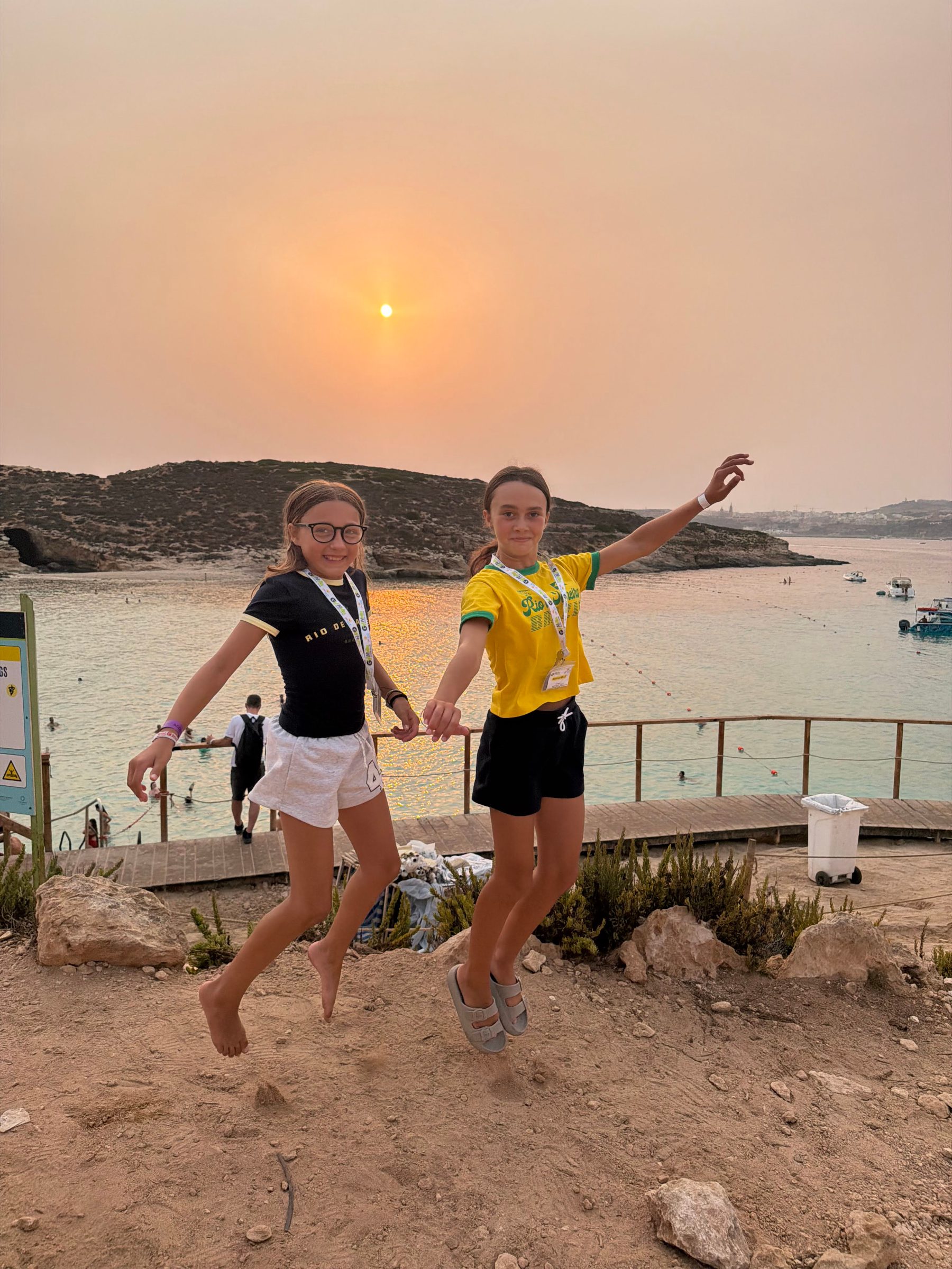 Junior summer camp students jumping for joy at sunset by Malta's Blue Lagoon