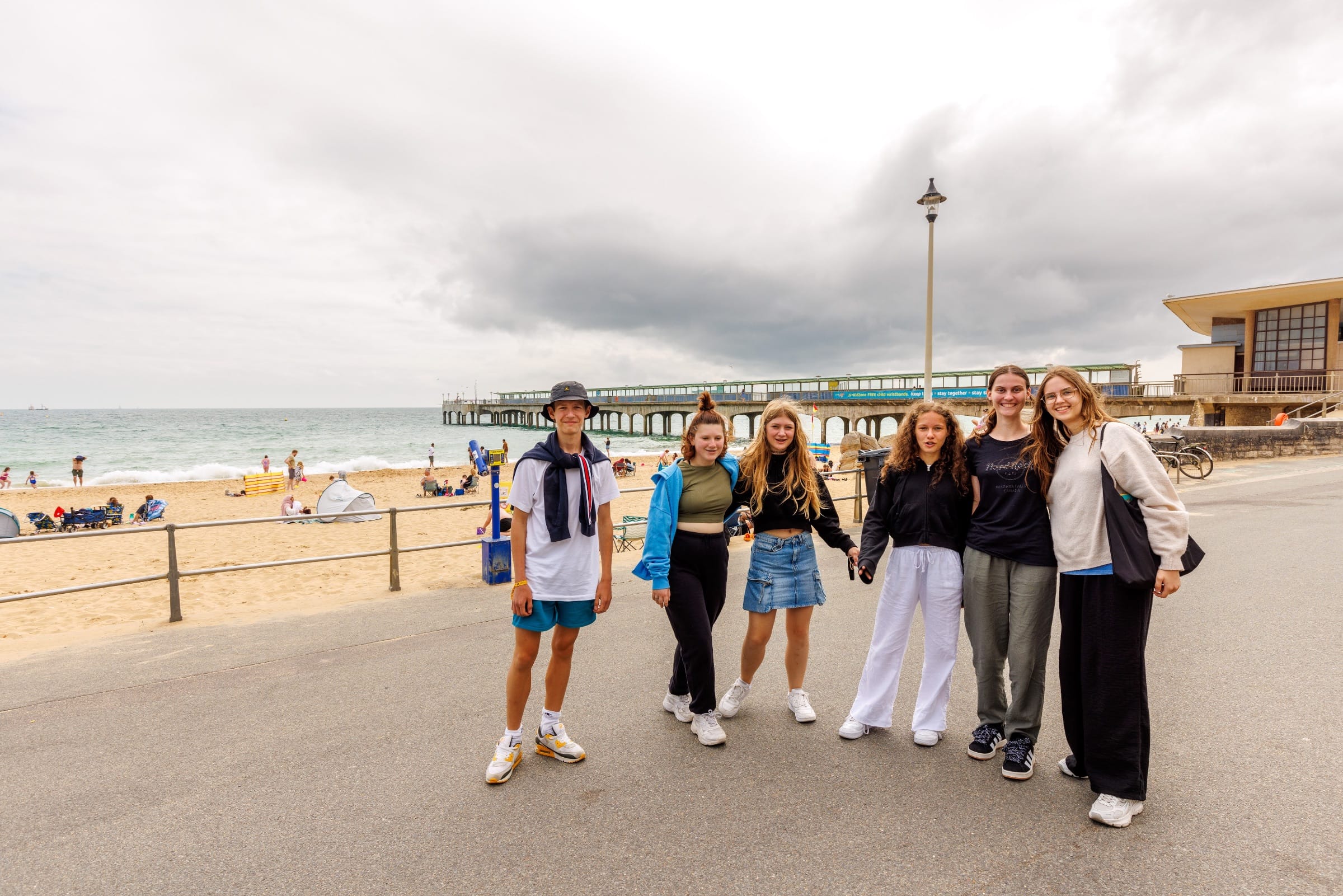 Junior summer camp students posing on Bournemouth promenade with the pier and beach behind them